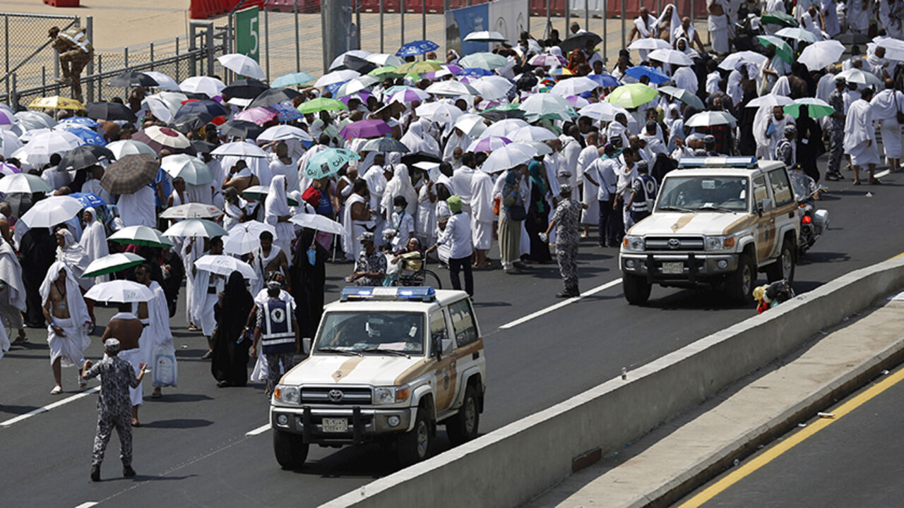 SAUD-HAJ/ Police vehicles drive past pilgrims on a road in Mina, near the holy city of Mecca September 24, 2015. At least 310 pilgrims were killed on Thursday in a crush at Mina, outside the Muslim holy city of Mecca, where some two million people are performing the annual Haj pilgrimage, Saudi authorities said. REUTERS/Ahmad Masood - RTX1S7WW
