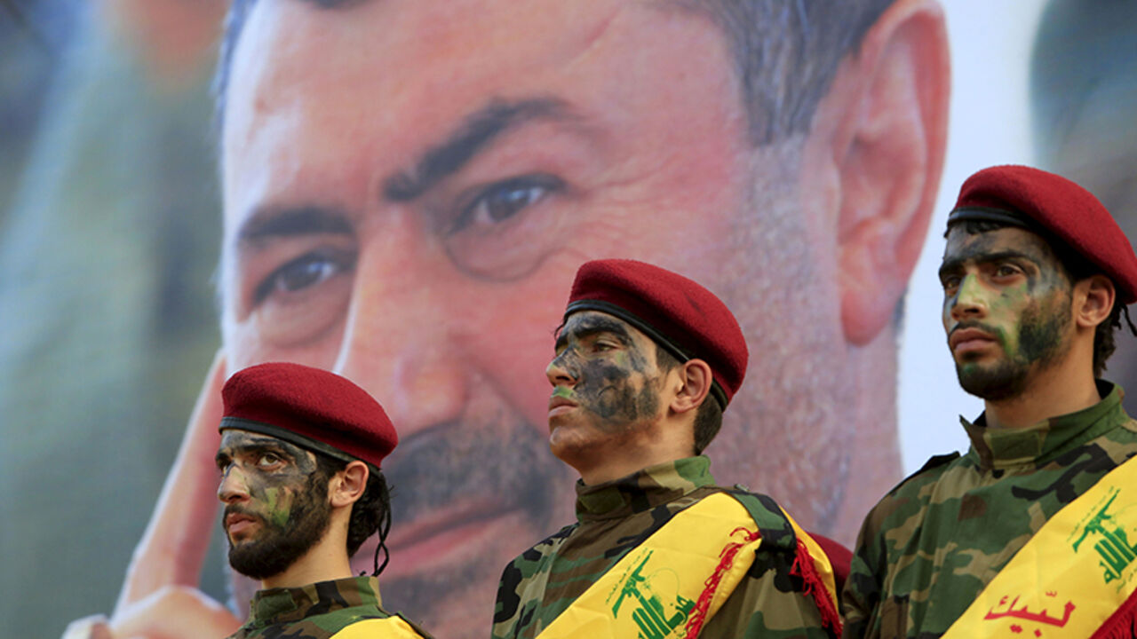 MIDEAST-CRISIS/SYRIA-LEBANON-HEZBOLLAH Lebanon's Hezbollah members stand at attention in front of a picture of Hassan al-Haj, one of Hezbollah's top commanders who was killed fighting alongside Syrian army forces in Idlib province, during his funeral in his hometown of al-Luwaizeh, southern Lebanon October 12, 2015. Lebanon's Hezbollah on Monday buried a commander described as the group's most important military figure to be killed in the four-year-long Syrian war. Hassan al-Haj was killed in Idlib province in northwestern Syria, where the Irani