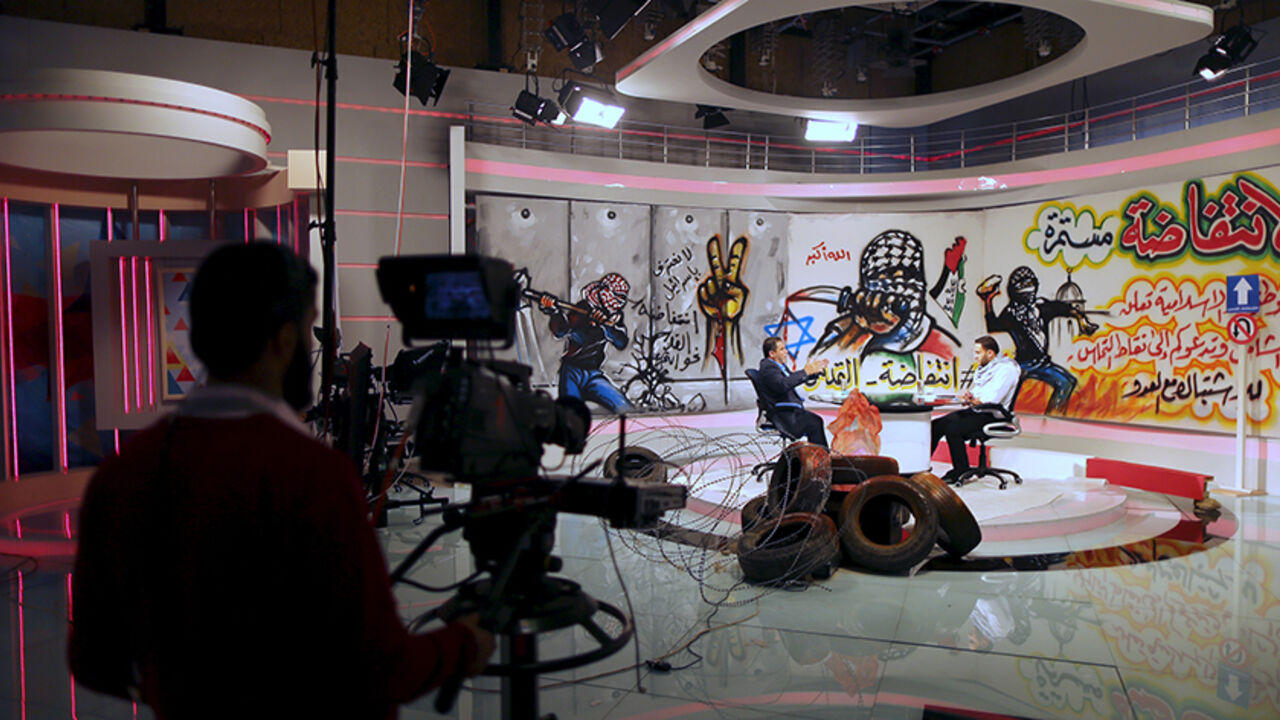 ISRAEL-PALESTINIANS/HAMAS Palestinian presenter Raji Al-Hams (R) listens to Hamas official Salah al-Bardweel at the studio of Hamas-run Al-Aqsa TV in Gaza City October 27, 2015. The studio of Hamas-run Al-Aqsa TV is decorated with slogans praising the "knife intifada" against Israel. Video clips and rousing songs glorify the daily attacks, while the presenters all wear black-and-white Keffiyeh scarves. REUTERS/Mohammed Salem - RTX1TG21