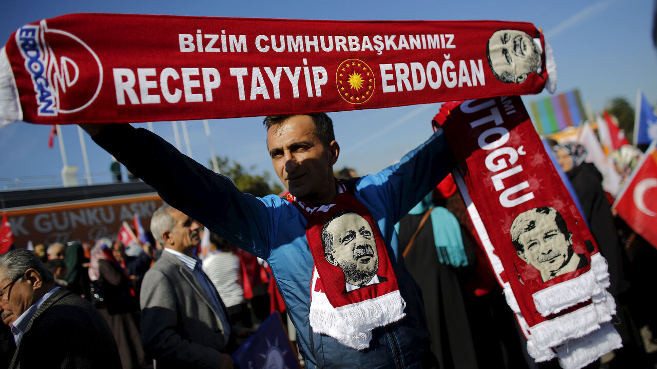 TURKEY-ELECTION/ A man holds scarves bearing the names and images of Turkish Prime Minister Ahmet Davutoglu (R) and President Tayyip Erdogan as supporters of the AK Party gather to wait for the arrival of Davutoglu in Istanbul, Turkey November 3, 2015. Erdogan said on Monday the nation had voted for stability in a parliamentary election that saw the AK Party he founded win almost 50 percent of the vote, and said the world should respect the result. REUTERS/Murad Sezer - RTX1UIYW