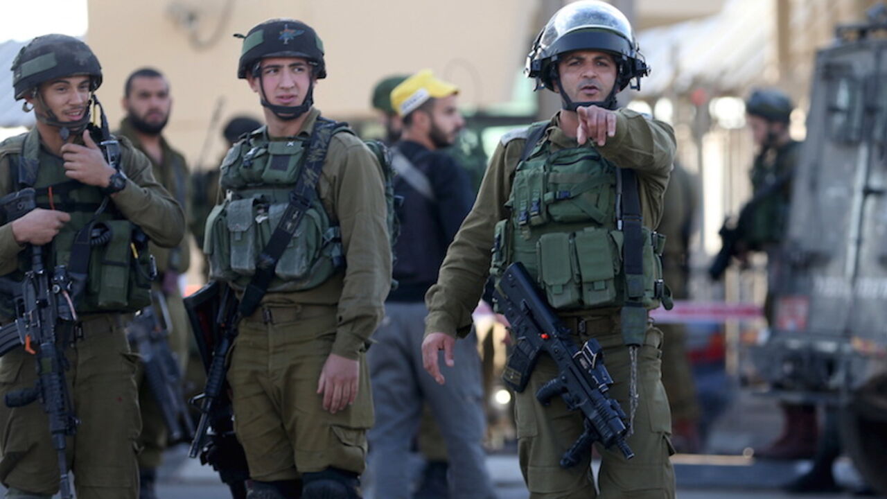 ISRAEL-PALESTINIANS/ An Israeli soldier gestures as he stands guard with others at the scene of what an Israeli police spokeswoman said was a car-ramming attempt by a Palestinian at the West Bank checkpoint of Qalandia, near Ramallah, December 18, 2015. REUTERS/Mohamad Torokman - RTX1ZANG
