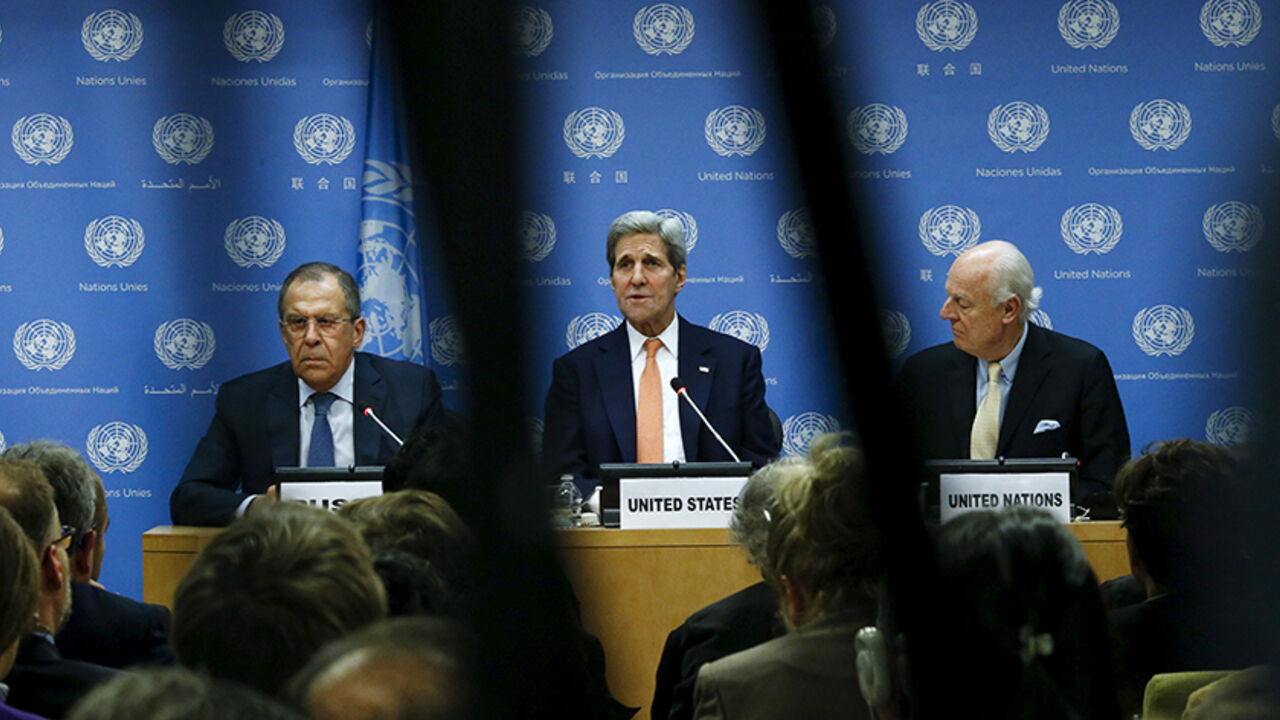 MIDEAST-CRISIS/SYRIA-VOTE U.S. Secretary of State John Kerry (C) speaks to the media next to Russia's Foreign Minister Sergey Lavrov (L) and Special Envoy of the Secretary-General for Syria Staffan de Mistura during a news conference at the United Nations Headquarters in Manhattan, New York, December 18, 2015. The United Nations Security Council on Friday unanimously agreed a resolution endorsing an international roadmap for a Syria peace process, a rare show of unity among major powers on a conflict that has claimed more than a qua