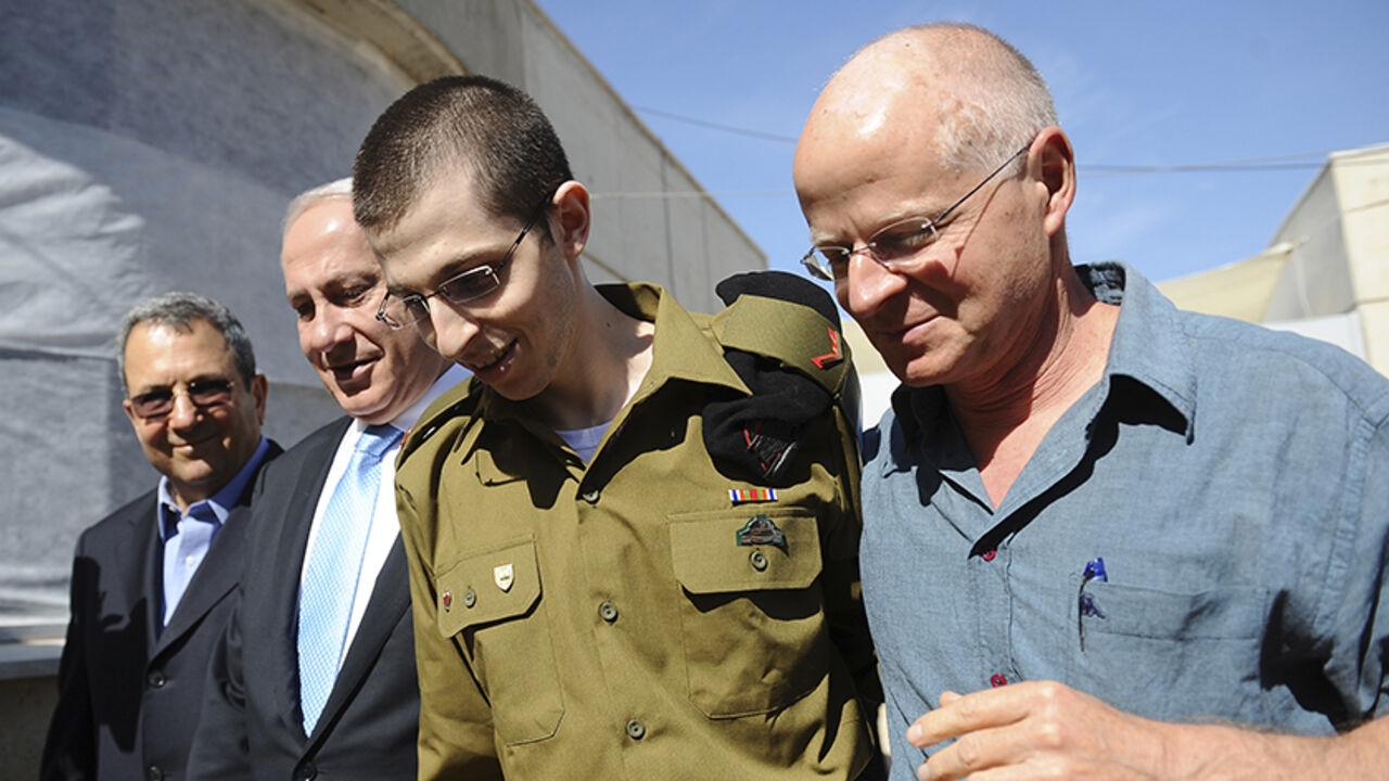 PALESTINIANS-ISRAEL/ Gilad Shalit (2nd R) walks with his father Noam (R), Israel's Prime Minister Benjamin Netanyahu and Defence Minister Ehud Barak (L) at Tel Nof air base in central Israel in this handout released by the Prime Minister's Office (PMO) October 18, 2011. Israeli soldier Gilad Shalit returned home to a national outpouring of joy on Tuesday after five years in captivity as hundreds of Palestinian prisoners exchanged for him were greeted with kisses from Hamas leaders in the Gaza Strip. REUTERS/PMO/Handout (ISRAEL