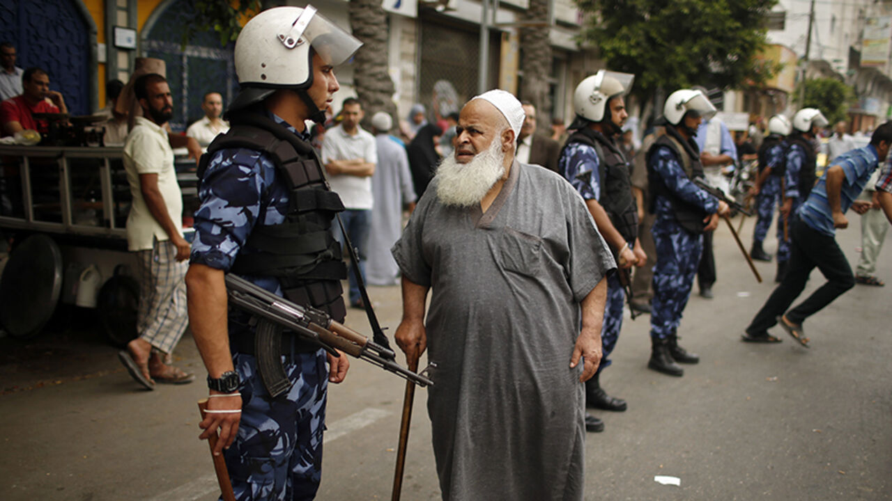 PALESTINIAN-UNITY/CRISIS A Palestinian employee paid by Palestinian Authority stands next to a policeman as he waits to receive his salary outside a closed bank in Gaza City June 5, 2014. A Palestinian unity government formed by President Mahmoud Abbas and the Islamist Hamas group faced its first and serious challenge on Thursday when civil servants of Hamas, who were not on the payment list, scuffled with those cashing their salaries. Civil servants employed by Hamas since 2007 arrived and prevented employees paid by the Palestini