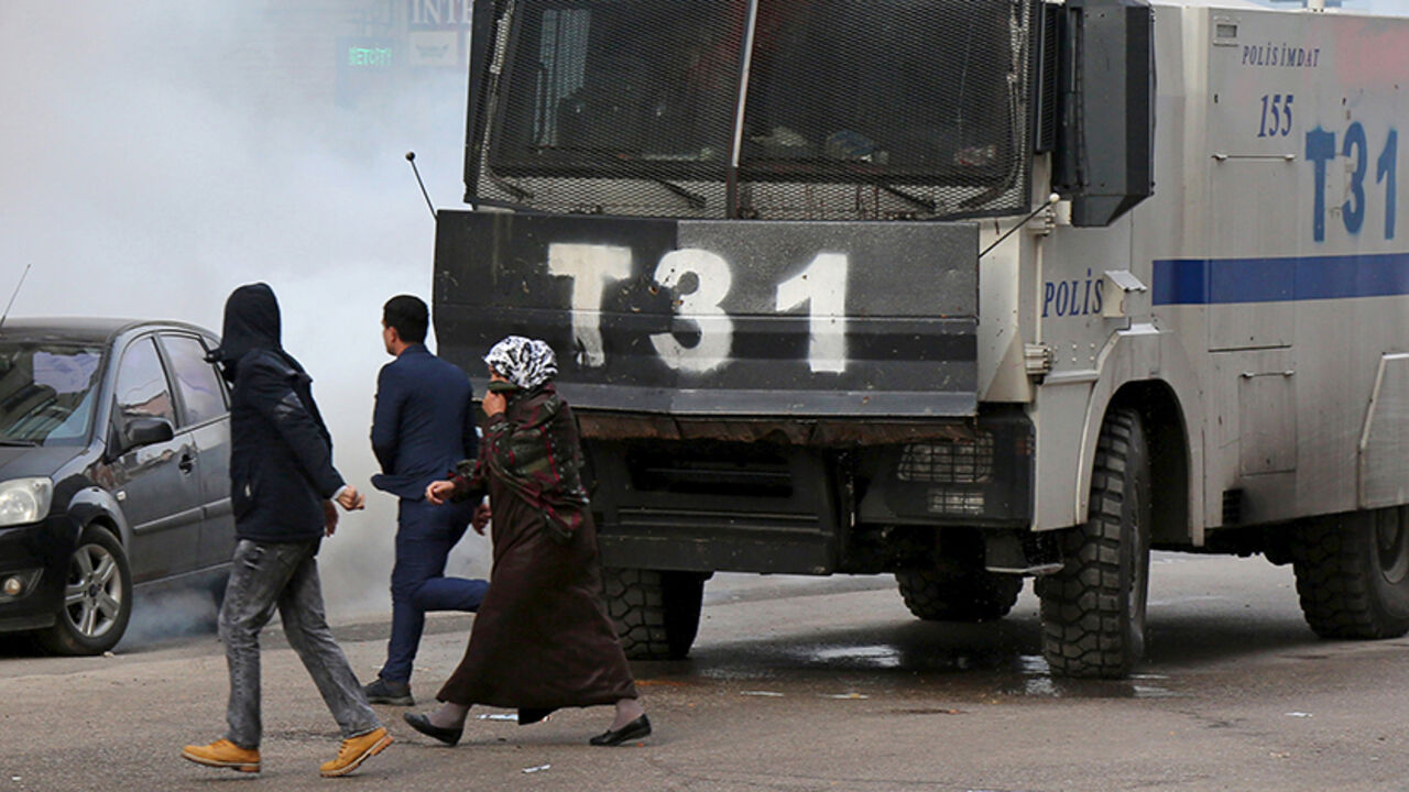 TURKEY-KURDS/ People walk past an armored police vehicle as Turkish riot police use tear gas to disperse Kurdish demonstrators during a protest against a curfew in Sur district and security operations in the region, in the southeastern city of Diyarbakir, Turkey January 17, 2016. REUTERS/Sertac Kayar - RTX22QXH