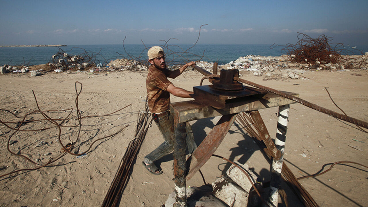 PALESTINIANS-ISRAEL/SCRAP A Palestinian worker straightens scrap metal collected from the rubble of a hotel in Gaza City that was destroyed during Israel's three-week offensive nearly two years ago November 7, 2010. Thousands of Gazans, mainly young men and boys, go close to a no-go border zone in the Gaza Strip daily to pick over the wreckage of factories and houses flattened by Israel in the past few years in its conflict with Islamist Hamas militants who control the enclave. REUTERS/Suhaib Salem (GAZA - Tags: POLITICS SOCIETY) -