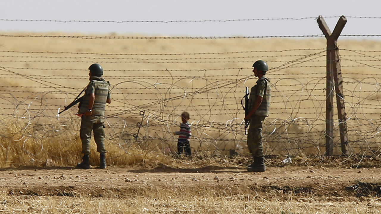 SYRIA-CRISIS/TURKEY-REFUGEES Turkish soldiers stand guard as a Syrian refugee boy waits behind the border fences to cross into Turkey on the Turkish-Syrian border, near the southeastern town of Akcakale in Sanliurfa province, Turkey, June 5, 2015. More than 3,000 Syrians fleeing clashes between Islamic State and Kurdish fighters have crossed into Turkey since Wednesday, a Turkish government official said. Kurdish forces are trying to drive the militants out of Tel Abyad, in Syria's Hassakah province, close to the Turkish border town of