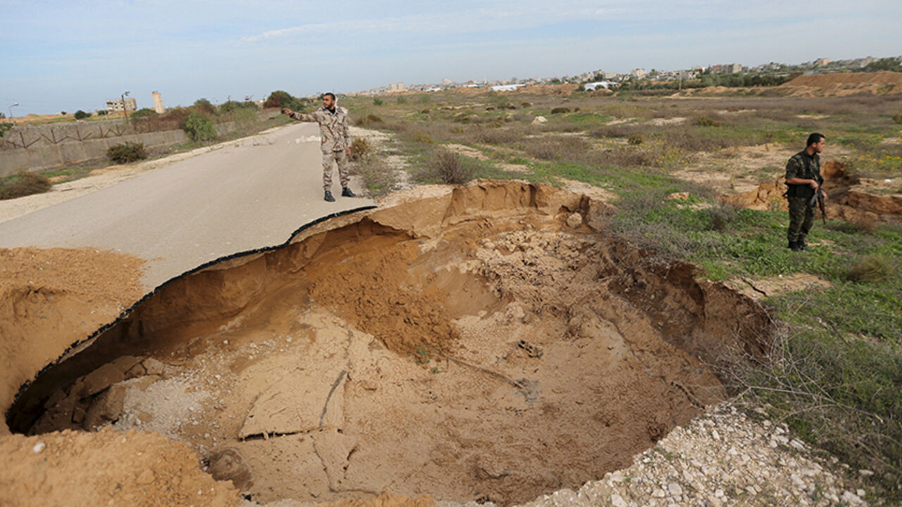 PALESTINIANS-EGYPT/TUNNELS Members of the Palestinian security forces loyal to Hamas stand guard as they view a landslide caused by floodwater pumped by Egyptian forces to destroy a network of Palestinian tunnels, near the border between Egypt and southern Gaza Strip November 26, 2015. REUTERS/Ibraheem Abu Mustafa - RTX1VYBN
