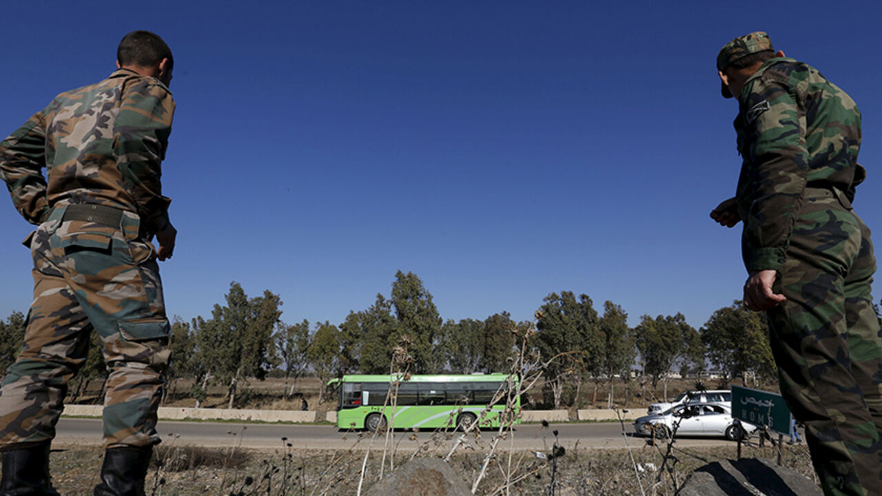 MIDEAST-CRISIS/HOMS-CEASEFIRE Syrian Army forces look on as buses leave district of Waer during a truce between the government and rebels, in Homs, Syria December 9, 2015. Scores of people left the last area held by insurgents in the Syrian city of Homs on Wednesday under a local truce between the government and rebels, a monitoring group said, a rare agreement in Syria's nearly five-year conflict. Three buses carrying people had left the previously besieged district of Waer, the Syrian Observatory for Human Rights said. About 750 peopl