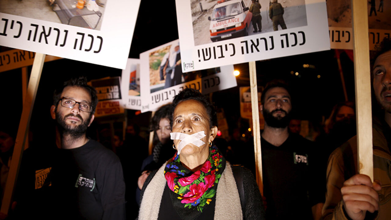 ISRAEL-NGOS-VIDEO Israeli left wing demonstrators march holding placards protesting the right wing incitement against President Reuven Rivlin and human rights activists in Tel Aviv. December 19, 2015. An ultra-nationalist Israeli group has published a video accusing the heads of four of Israel's leading human rights organisations of being foreign agents funded by Europe and supporting Palestinians "involved in terrorism". The sign reads, "That's how occupation looks like." REUTERS/Baz Ratner - RTX1ZETR