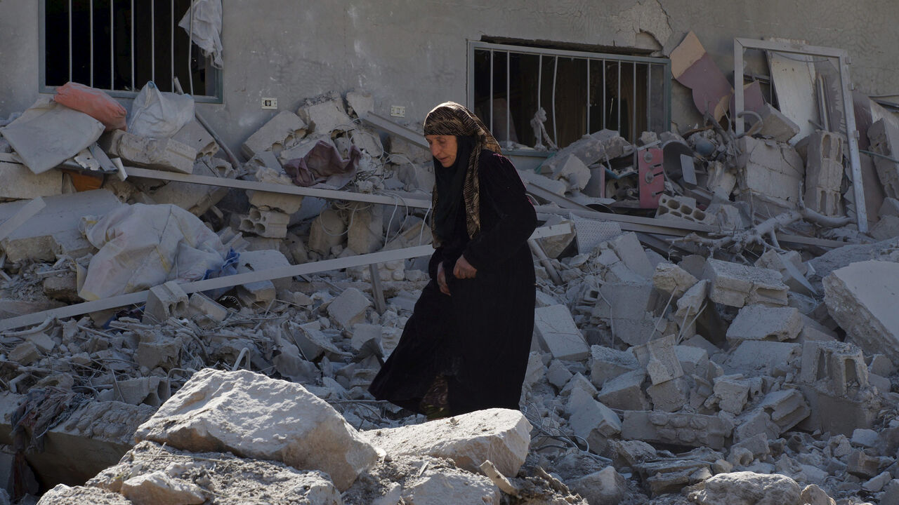 MIDEAST-CRISIS/SYRIA A woman makes her way through the rubble of damaged buildings after airstrikes by pro-Syrian government forces in the rebel held town of Dael, in Deraa Governorate, Syria February 12, 2016. REUTERS/Alaa Al-Faqir - RTX26N2E