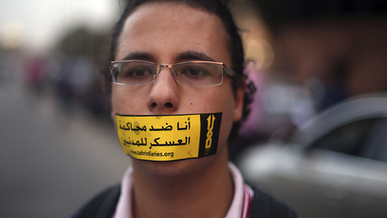 EGYPT-PROTEST/ A demonstrator looks on with a sign reading "I am against the military courts for civilians" taped over his mouth during a human chain by members of the April 6 movement and liberal activists against a law restricting demonstrations as well as the crackdown on activists and calling for the release of activists in detention in front of El-Thadiya Egyptian Presidential in Cairo, April 23, 2014. REUTERS/Amr Abdallah Dalsh (EGYPT - Tags: POLITICS CIVIL UNREST) - RTR3MD2M