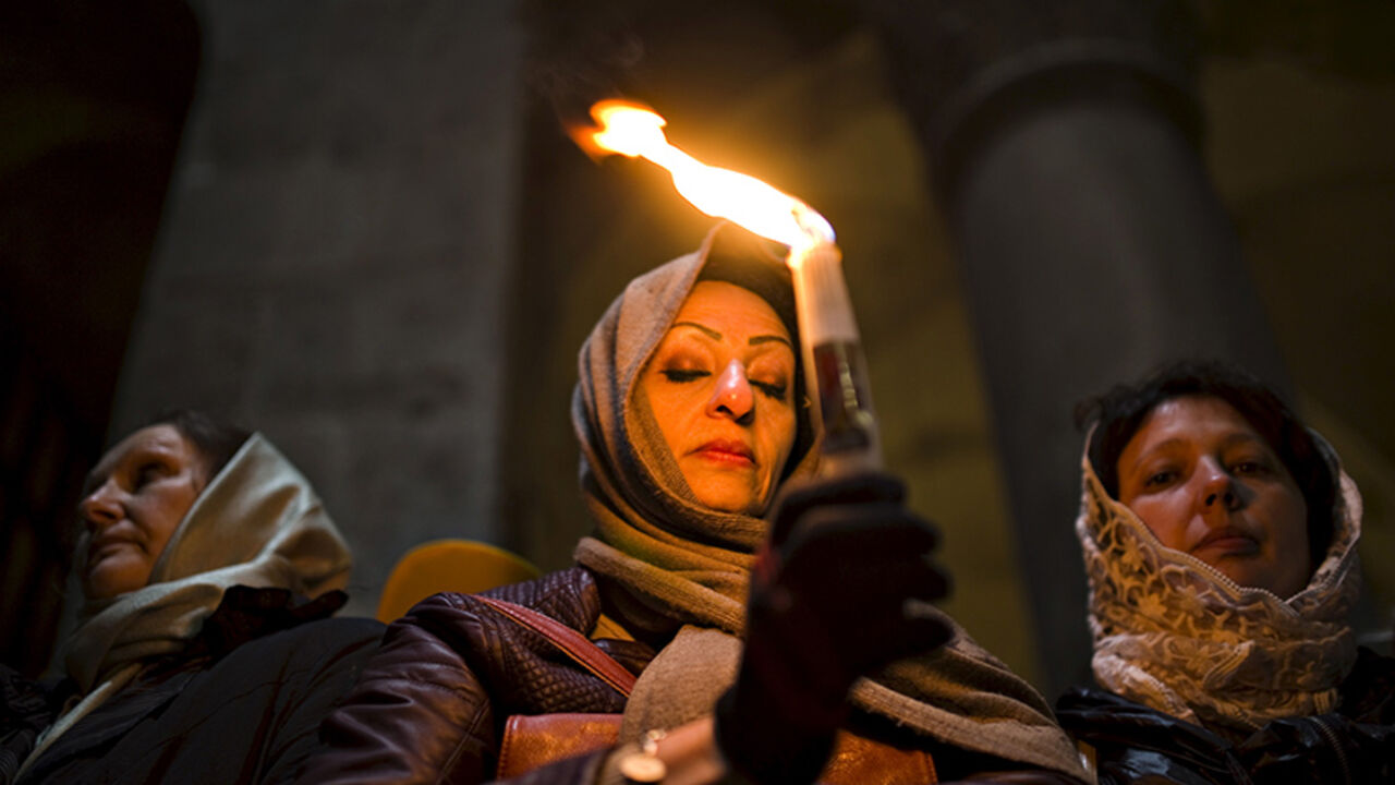ISRAEL-RELIGION/ A Christian worshipper holds a candle, before Easter Sunday mass procession inside the Church of the Holy Sepulchre in Jerusalem's old city April 12, 2015. REUTERS/Amir Cohen - RTR4X06K