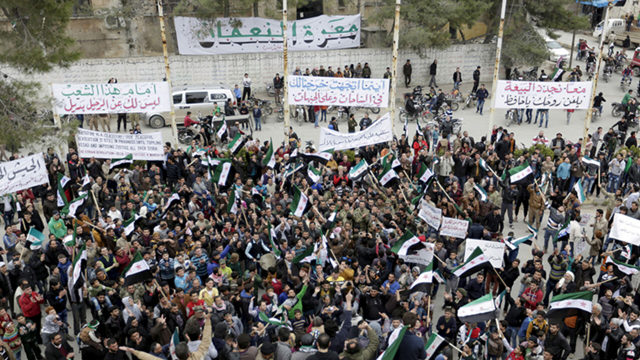 MIDEAST-CRISIS/SYRIA Protestors carry Free Syrian Army flags and chant slogans during an anti-government protest in the town of Marat Numan in Idlib province, Syria March 4, 2016. The text on the banners read in Arabic "Together we renew our pledge of allegiance, curse your soul Hafez" (top R), "Wherever you head to, we will go to the squares and the fronts" (top C) and "Before the people, you have no choice but to leave" (top L). REUTERS/Khalil Ashawi - RTS9AYC