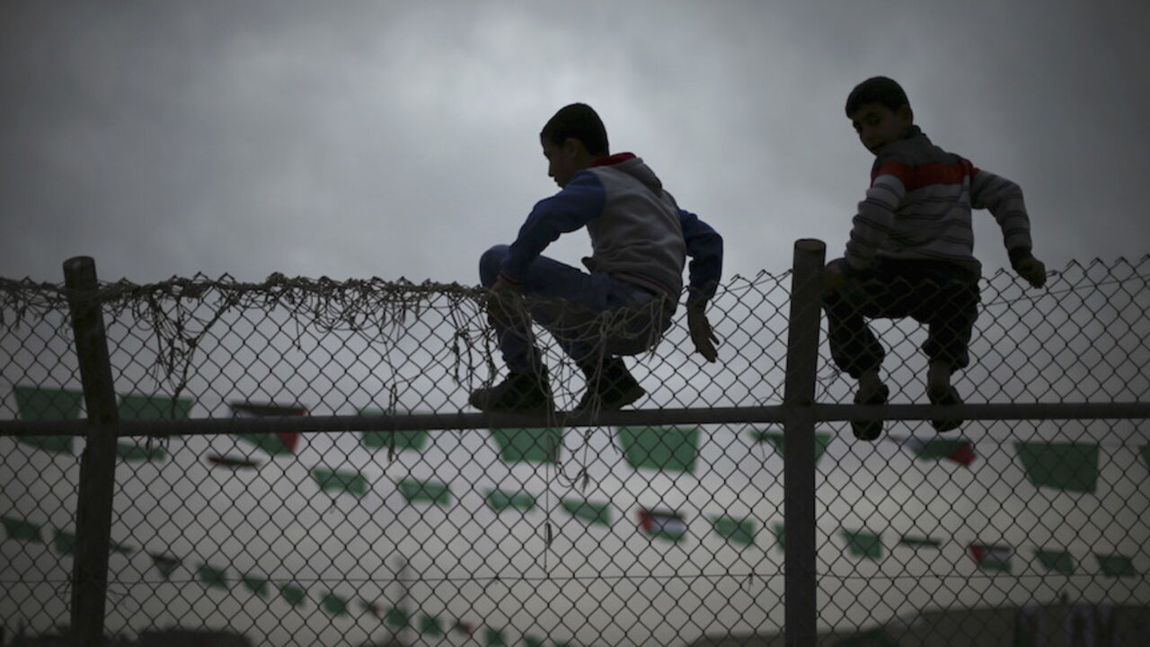 ISRAEL-PALESTINIANS/ Palestinian boys sit on a fence as they watch a Hamas rally in Khan Younis in the southern Gaza Strip January 7, 2016. The rally, organized by Hamas movement, was held to honor the families of dead Hamas militants, who Hamas's armed wing said participated in imprisoning Israeli soldier Gilad Shalit, organizers said. Shalt was abducted by militants in a cross-border raid in 2006, and was released in exchange for more than 1,000 Palestinians held in Israeli jails. REUTERS/Mohammed Salem - RTX21FR7
