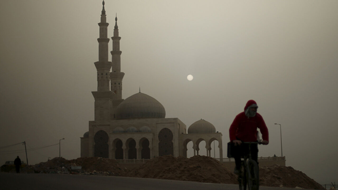 A Palestinian man rides his bicycle in front of a mosque on a stormy day in Gaza January 18, 2016. REUTERS/Mohammed Salem  - RTX22XLX