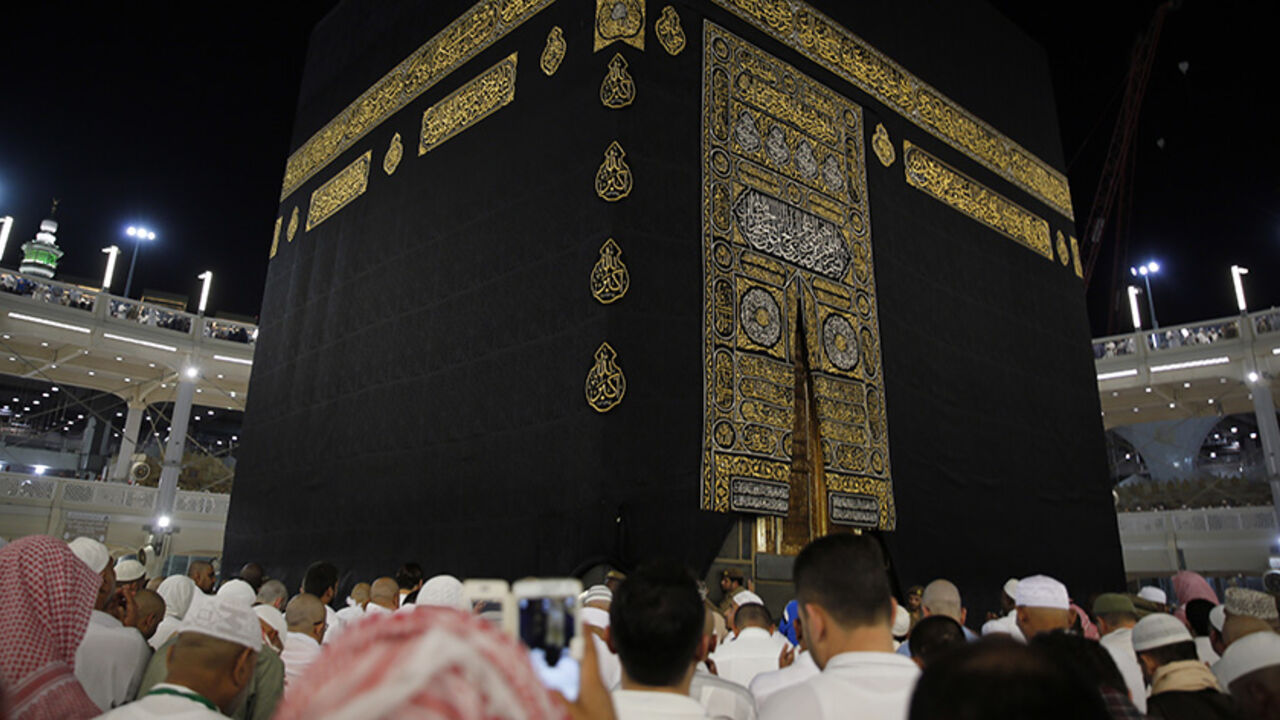 SAUDI-RELIGION/ A Saudi policeman (R) stands watch as muslims touch and pray at the door of the Kaaba and touch and kiss the al-Hajr al-Aswad "Black Stone" during their Umrah Mawlid al-Nabawi "Birthday of Prophet Mohammad" in the holy city of Mecca, Saudi Arabia January 18, 2016. Picture taken January 18, 2016. REUTERS/Amr Abdallah Dalsh - RTX25AB8