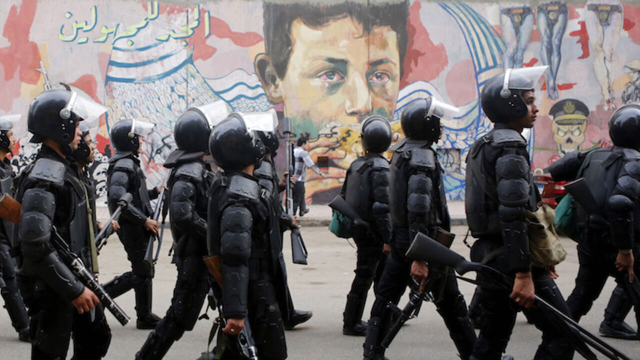 EGYPT-PROTESTS/ANNIVERSARY Riot police walk in front of graffiti representing anti-military power and Egypt's unrest, which reads "Glory to the unknown", along Mohamed Mahmoud Street during the third anniversary of violent and deadly clashes near Tahrir Square in Cairo November 19, 2014. Egyptian police arrested 25 individuals after four hundred protestors staged a march through downtown Cairo on the anniversary of deadly clashes with security forces three years ago, the interior ministry said on Wednesday. REUTERS/Amr Abdallah Dals