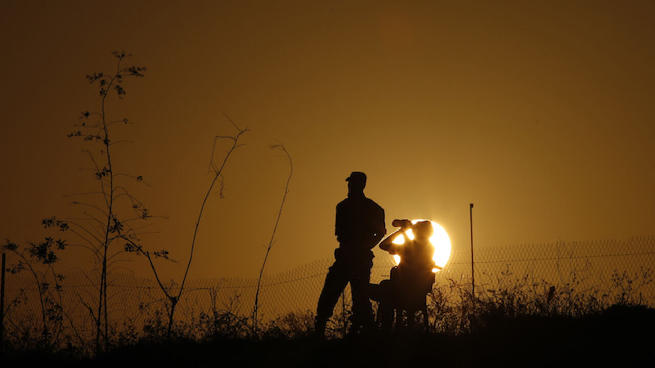 MIDEAST-PALESTINIANS/ISRAEL A Palestinian Islamic Jihad militant drinks water as another stands guards during a military drill at sunset in the southern Gaza Strip December 11, 2014. REUTERS/Suhaib Salem (GAZA - Tags: POLITICS CIVIL UNREST MILITARY) - RTR4HNV1
