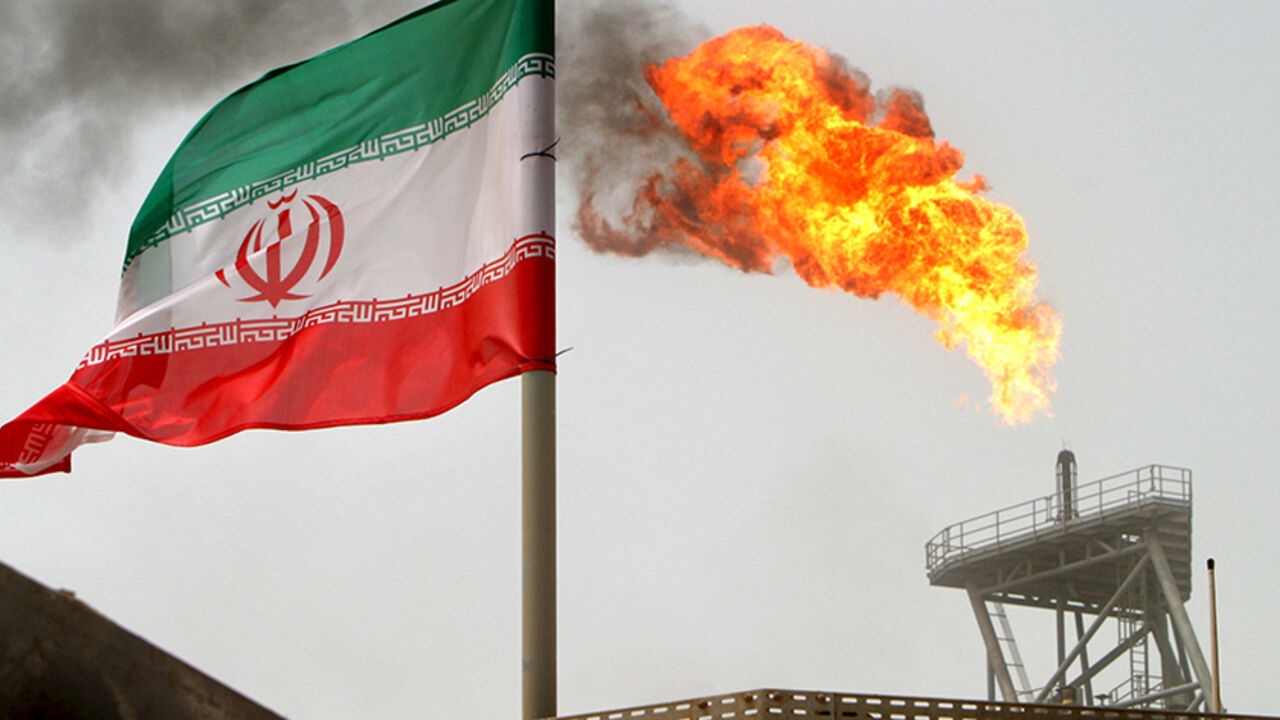 IRAN-SHIPPING/OIL A gas flare on an oil production platform in the Soroush oil fields is seen alongside an Iranian flag in the Gulf July 25, 2005. REUTERS/Raheb Homavandi/File Photo - RTX2AOPF