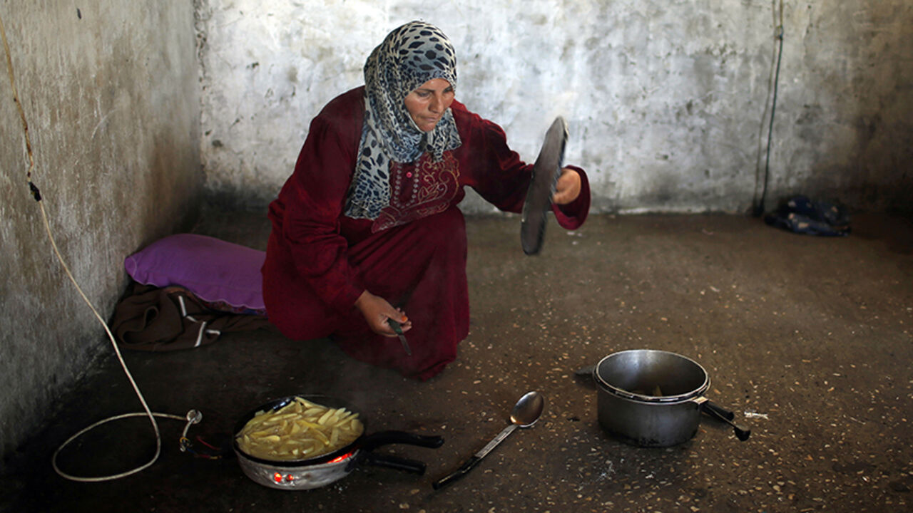 PALESTINIANS/ A Palestinian woman cooks at her house in the northern Gaza Strip May 26, 2014. REUTERS/Mohammed Salem (GAZA - Tags: SOCIETY) - RTR3QYQN