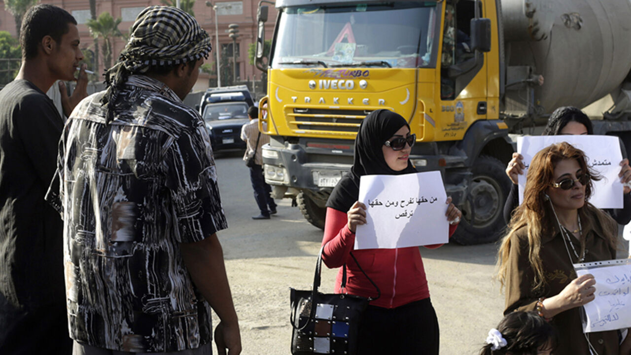 EGYPT-HARASSMENT Men look at female protesters carrying signs against sexual harassment, after a woman was sexually assaulted by a mob during Sunday's celebrations marking the new president's inauguration, in Tahrir square in Cairo June 11, 2014. Egyptian authorities have arrested seven men for sexually harassing women near Cairo's Tahrir Square while thousands celebrated the inauguration of President Abdel Fattah al-Sisi, the Interior Ministry said on Monday. A video posted on YouTube on Sunday, claiming to depict one of