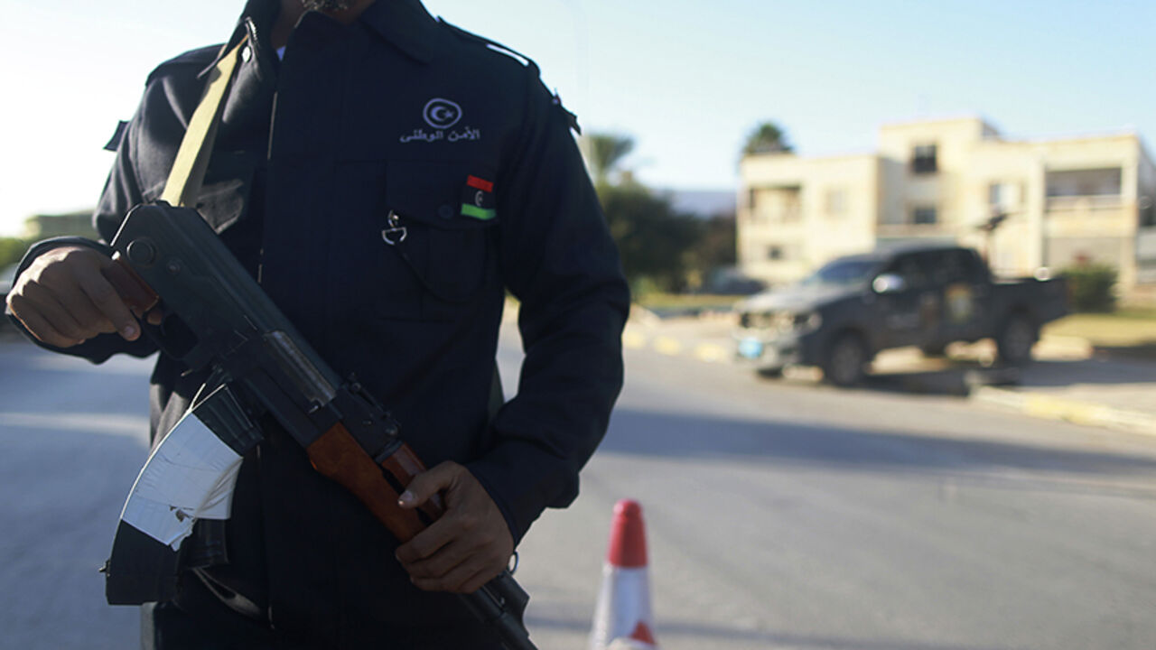 LIBYA-SECURITY/ A security officer stands with his weapon on a road leading to a police station in Benghazi December 4, 2014. Police stations, prisons and the local security headquarters have reopened in Libya's eastern city of Benghazi for the first time in over a year, officials said, after pro-government forces seized back part of the port city. Medics say around 450 people have been killed in a two-month offensive by pro-government forces which has restored some sense of normality in parts of the city, though fighting