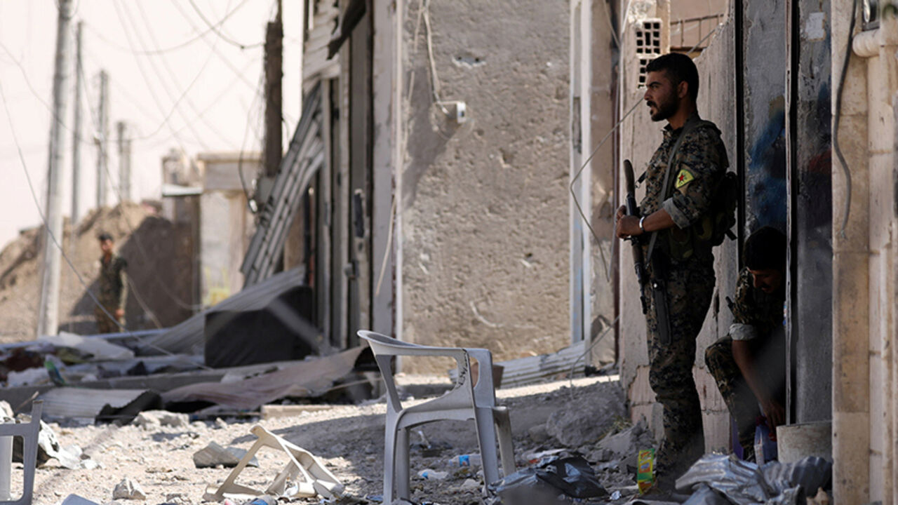 MIDEAST-CRISIS/SYRIA-RAQQA Syrian Democratic Forces (SDF) fighters stand along a damaged street in the Raqqa's al-Sanaa industrial neighbourhood, Syria June 14, 2017. Picture taken June 14, 2017. REUTERS/Rodi Said - RTS175OT
