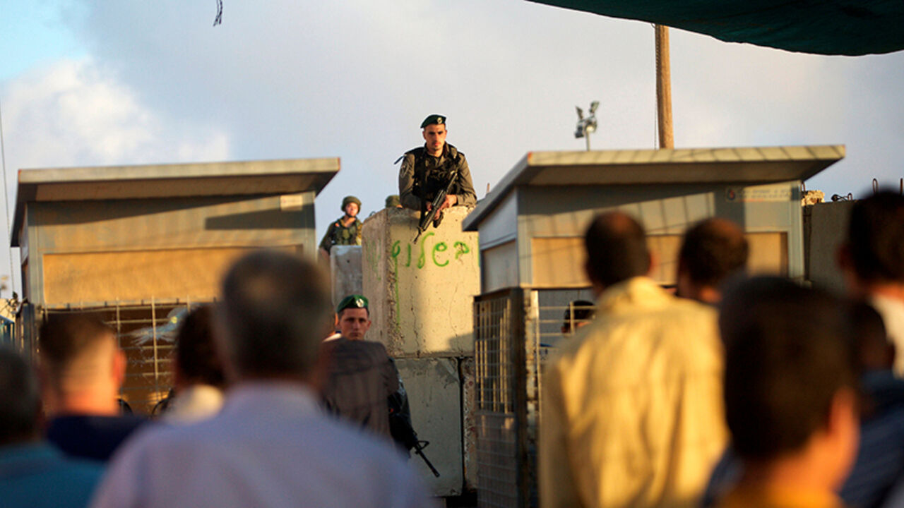 RELIGION-RAMADAN/ Israeli border police officers stand guard as Palestinians wait to cross through the Qalandia checkpoint to make their way to attend the first Friday prayer of the holy fasting month of Ramadan in Jerusalem's al-Aqsa mosque, near the West Bank city of Ramallah June 10, 2016. REUTERS/Mohamad Torokman - RTSGUJL