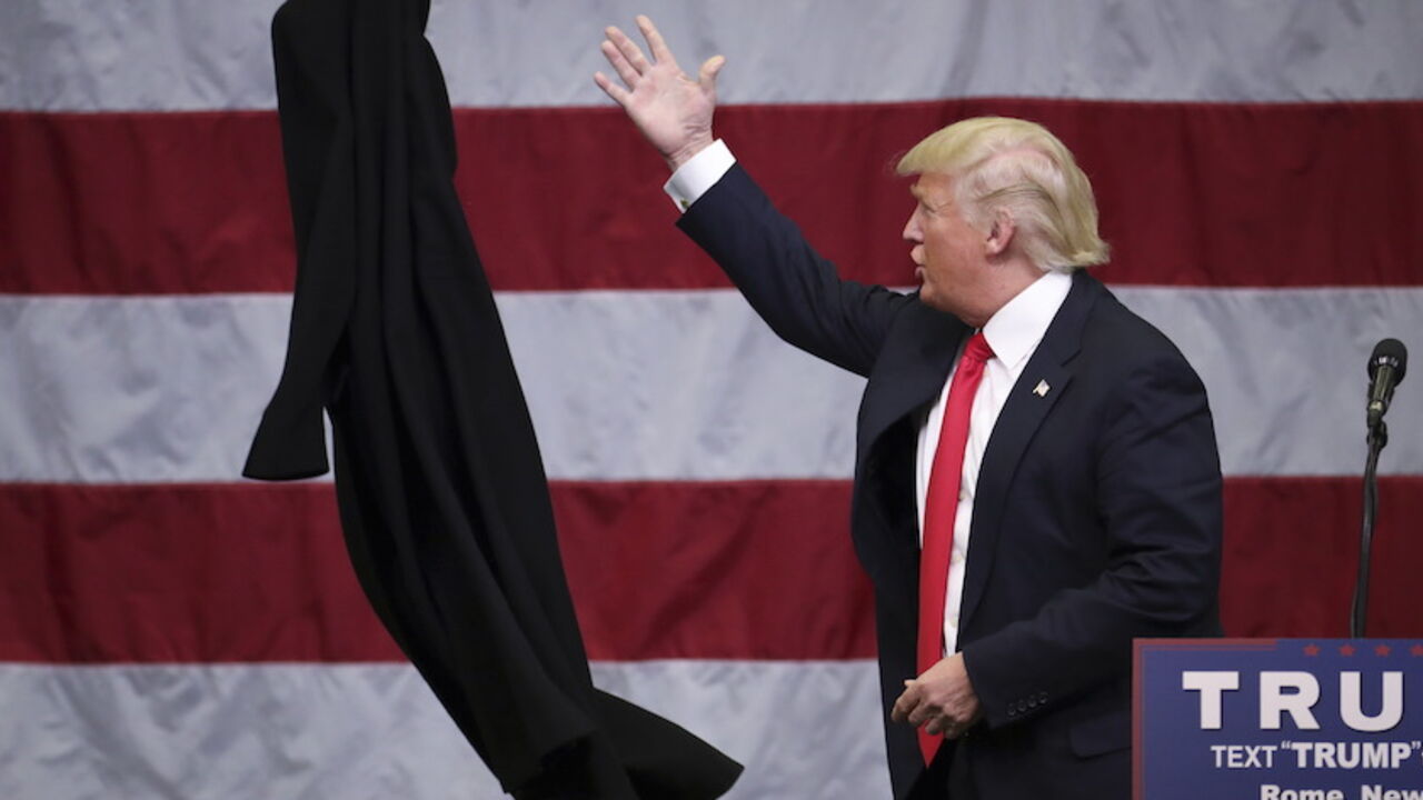 USA-ELECTION/TRUMP U.S. Republican presidential candidate Donald Trump tosses off his overcoat as he speaks at a campaign event in an airplane hangar in Rome, New York April 12, 2016. REUTERS/Carlo Allegri TPX IMAGES OF THE DAY - RTX29ODW