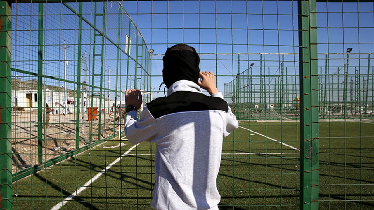MIDEAST-CRISIS/IRAQ-CHILDREN A Yazidi boy, 16, who was trained by Islamic State, wraps his head in a scarf as he stands by the fence of a playground at a refugee camp near the northern Iraqi city of Duhok April 19, 2016. The stories of boys from the minority Yazidi community now living in a refugee camp near the northern Iraqi city of Duhok appear to show efforts by Islamic State to create a new generation of fighters loyal to the group's ideology and inured to its extreme violence. The training often leaves them scarred, even after re