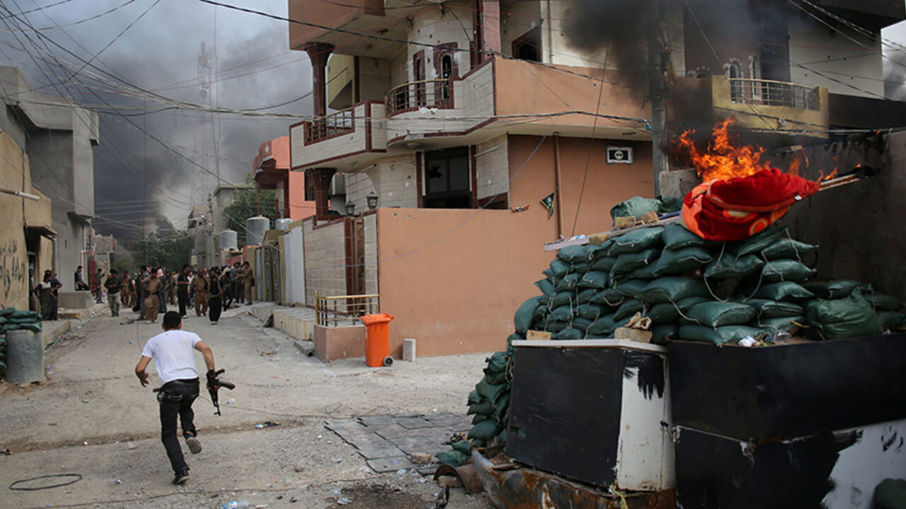 MIDEAST-CRISIS/IRAQ-TOWN A Kurdish gunman runs across a street in Tuz Khurmato during clashes between Shi'ite militia and Kurdish gunmen, Iraq, April 24, 2016. REUTERS/Goran Tomasevic/File Photo - RTX2EY4S