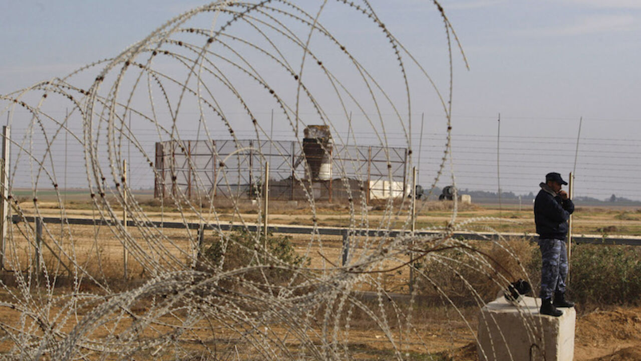 A member of the Hamas security forces stands guard as an Israeli watchtower (rear) is seen near the fence between Israel and the southern Gaza Strip November 24, 2012. Hamas Islamists enforced a fragile two-day-old truce on Friday by evacuating Palestinians from a "no-go" border zone after Israel shot dead a Gaza resident there in the first fatality since the ceasefire. REUTERS/ Ibraheem Abu Mustafa (GAZA - Tags: POLITICS CIVIL UNREST) - RTR3ATBQ