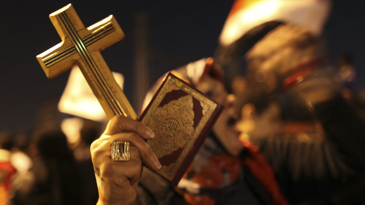 EGYPT-POLITICS/ A woman holds a copy of the Koran and a cross as she shouts slogans during a demonstration against Egypt's President Mohamed Mursi in front of the presidential palace in Cairo December 18, 2012. Opponents of Mursi staged protests in Cairo on Tuesday against an Islamist-backed draft constitution that has divided Egypt but looks set to be approved in the second half of a referendum this weekend. REUTERS/Khaled Abdullah (EGYPT - Tags: POLITICS CIVIL UNREST RELIGION TPX IMAGES OF THE DAY) - RTR3BQ8Q