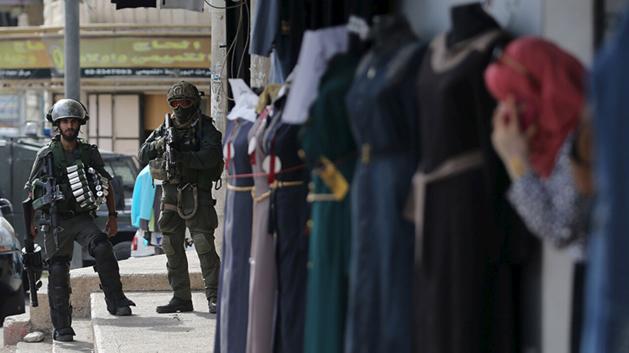 ISRAEL-PALESTINIANS/VIOLENCE Israeli border policemen take position as a Palestinian woman looks out a shop during clashes in the West Bank town of Al-Ram, near Jerusalem October 22, 2015. Nine Israelis have been killed in Palestinian stabbings, shootings and vehicle attacks since the start of October. Forty-nine Palestinians, including 25 assailants, among them children, have been killed in attacks and during anti-Israeli protests. Among the causes of the turmoil is Palestinians' anger at what they see as Jewish encroachment on the al