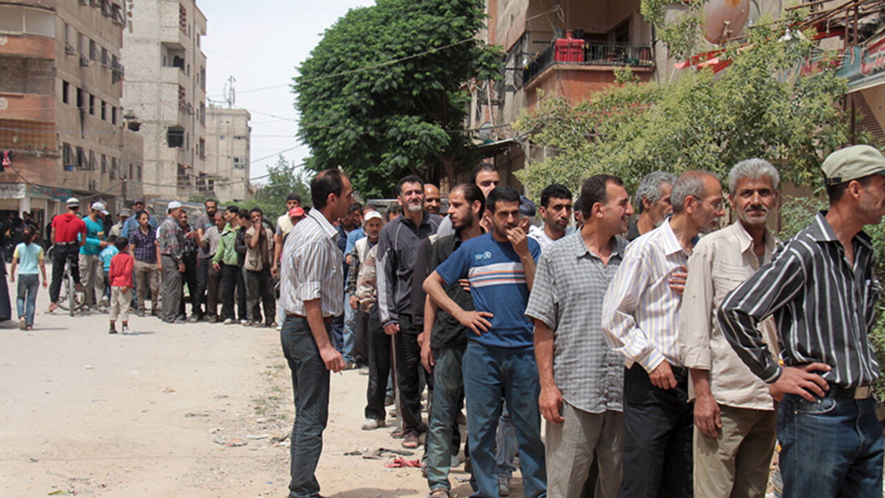 MIDEAST-CRISIS/SYRIA Residents and Palestinians who fled the Yarmouk refugee camp wait in line to receive parcels of humanitarian aid from the United Nations Relief and Works Organization (UNRWA) in the beseiged southern outskirts of Damascus May 23, 2015. REUTERS/Ward Al-Keswani - RTX1E8VS