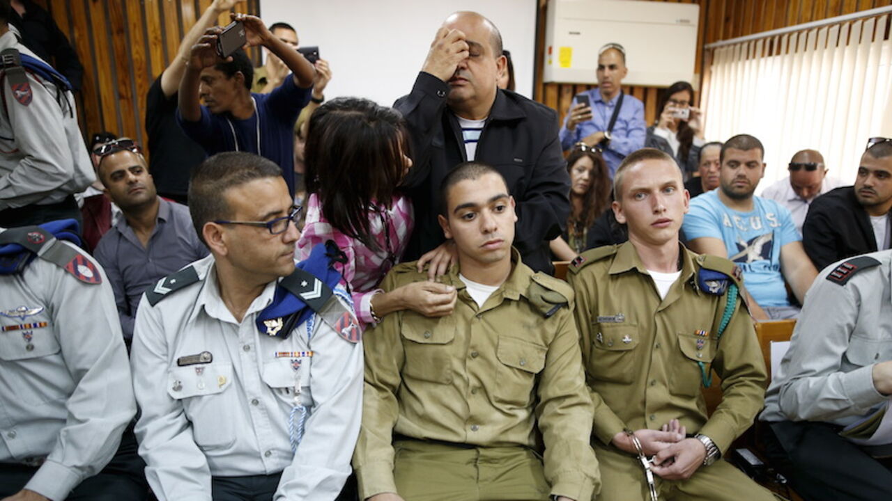 The father of an Israeli soldier who is charged with manslaughter, prays behind him in a military court during a remand hearing in Kiryat Malachi The father (C, back) of Israeli soldier Elor Azaria (C, seated), who is charged with manslaughter by the Israeli military after he shot a wounded Palestinian assailant as he lay on the ground in Hebron on March 24, prays behind him in a military court during a remand hearing for his case, near the southern Israeli city of Kiryat Malachi, March 31, 2016. Picture taken March 31, 2016. REUTERS/Amir Cohen - RTX2AHZ0