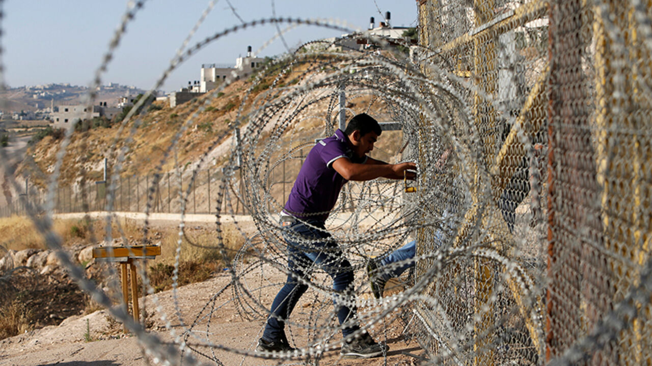 ISRAEL-PALESTINIANS/ Palestinians pass through an opening in the Israeli barrier fence as they attempt to make their way to attend the third Friday prayer of the holy fasting month of Ramadan in Jerusalem's al-Aqsa mosque, near the West bank city of Bethlehem June 24, 2016. REUTERS/Mussa Qawasma TPX IMAGES OF THE DAY - RTX2HXNV