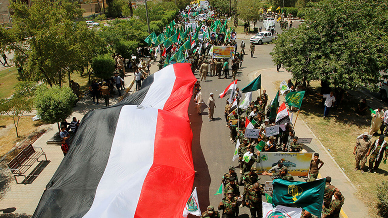 RELIGION-RAMADAN/ Iraqi Shi'ite Muslims from Hashid Shaabi (Popular Mobilization) march along a street as they hold a giant Iraqi flag during a parade marking the annual al-Quds Day, or Jerusalem Day, during the Muslim holy month of Ramadan in Baghdad, Iraq July 1, 2016. REUTERS/Khalid al Mousily - RTX2J7X3
