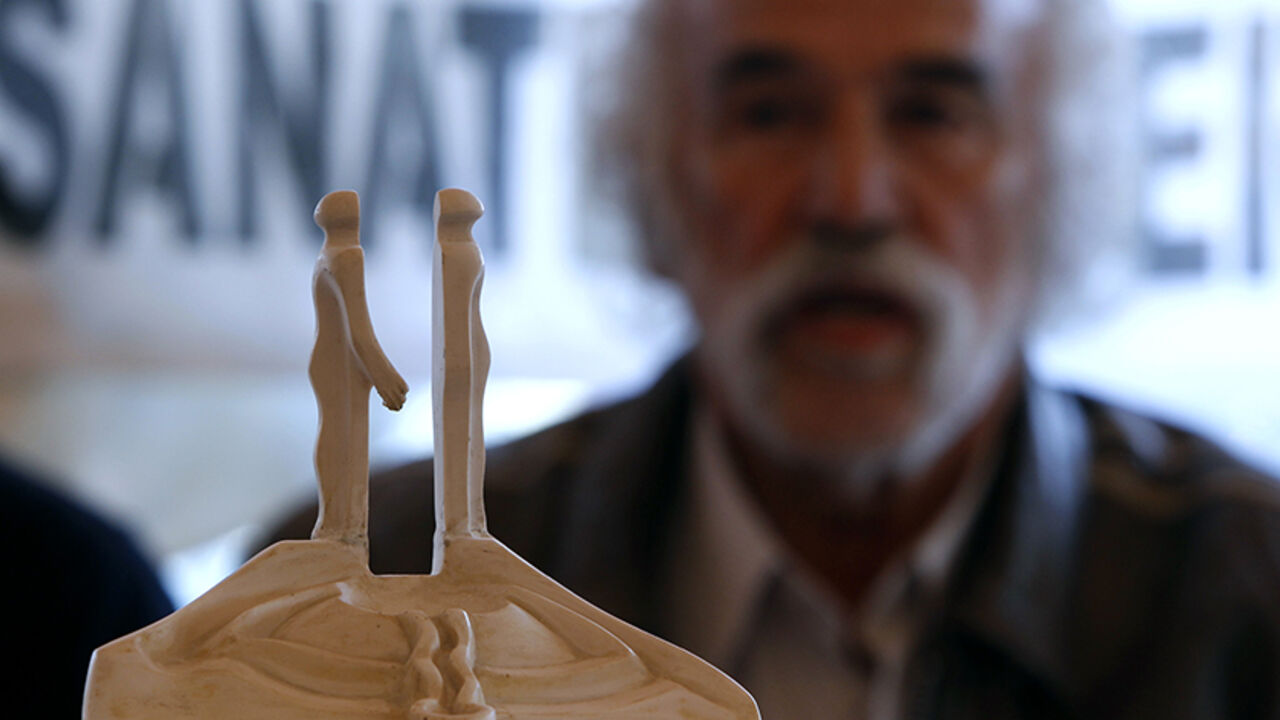 TURKEY-MONUMENT/ Turkish artist Mehmet Aksoy is seen behind a model of his sculpture during a news conference in Istanbul January 12, 2011. The fate of a giant peace monument symbolising reconciliation between Turks and Armenians has caused a row in Turkey after Prime Minister Tayyip Erdogan branded it "monstrous" and called for its demolition. The unfinished monument by renowned Turkish sculptor Aksoy consists of two concrete figures more than 30 metres high who face each other on an hill in the northeastern city of Kars.