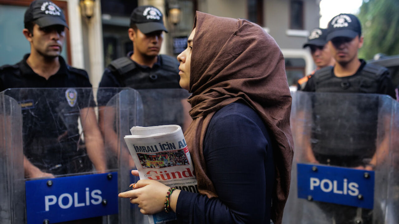 TURKEY-POLITICS-MILITARY-COUP-MEDIA-KURDS A woman holds a "Ozgur Gundem" newspaper in front of a police barricade on August 16, 2016 in Istanbul.
A Turkish court has ordered the temporary closure of a newspaper accusing it of links with Kurdish militants and spreading terrorist propaganda. / AFP / YASIN AKGUL (Photo credit should read YASIN AKGUL/AFP/Getty Images)