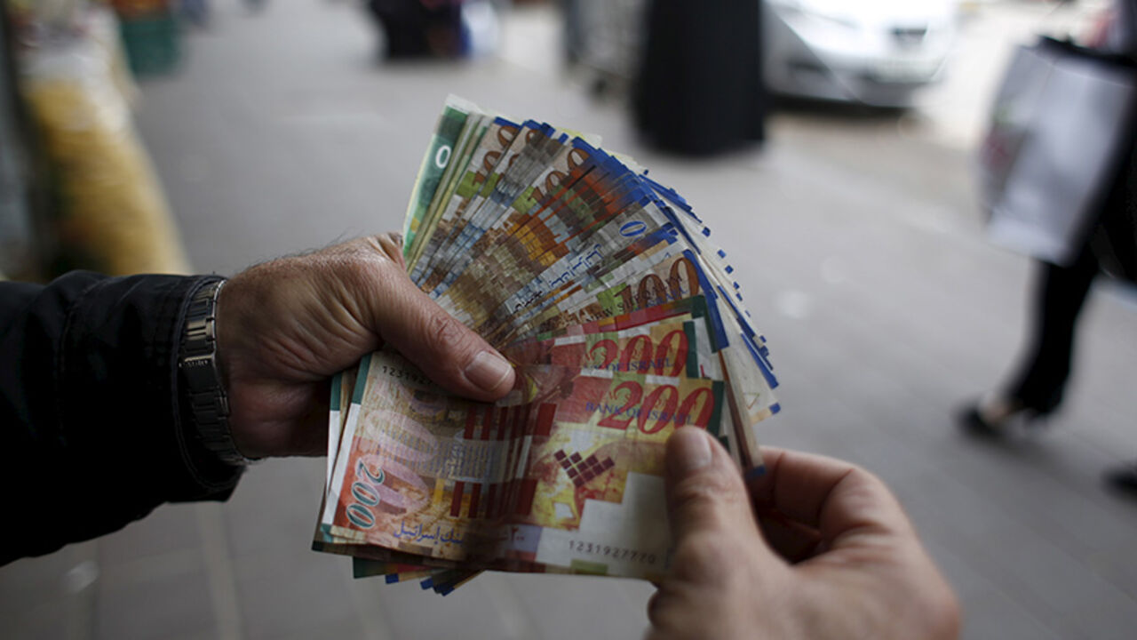 PALESTINIANS-ECONOMY/WESTBANK A Palestinian money exchanger displays money at a market in the West Bank city of Ramallah March 25, 2015. Israel's decision to withhold $130 million a month in revenue collected on behalf of the Palestinians is strangling the economy and leaving the banking system dangerously exposed, the Palestinian central bank governor said on Wednesday. REUTERS/Mohamad Torokman - RTR4UT7Y