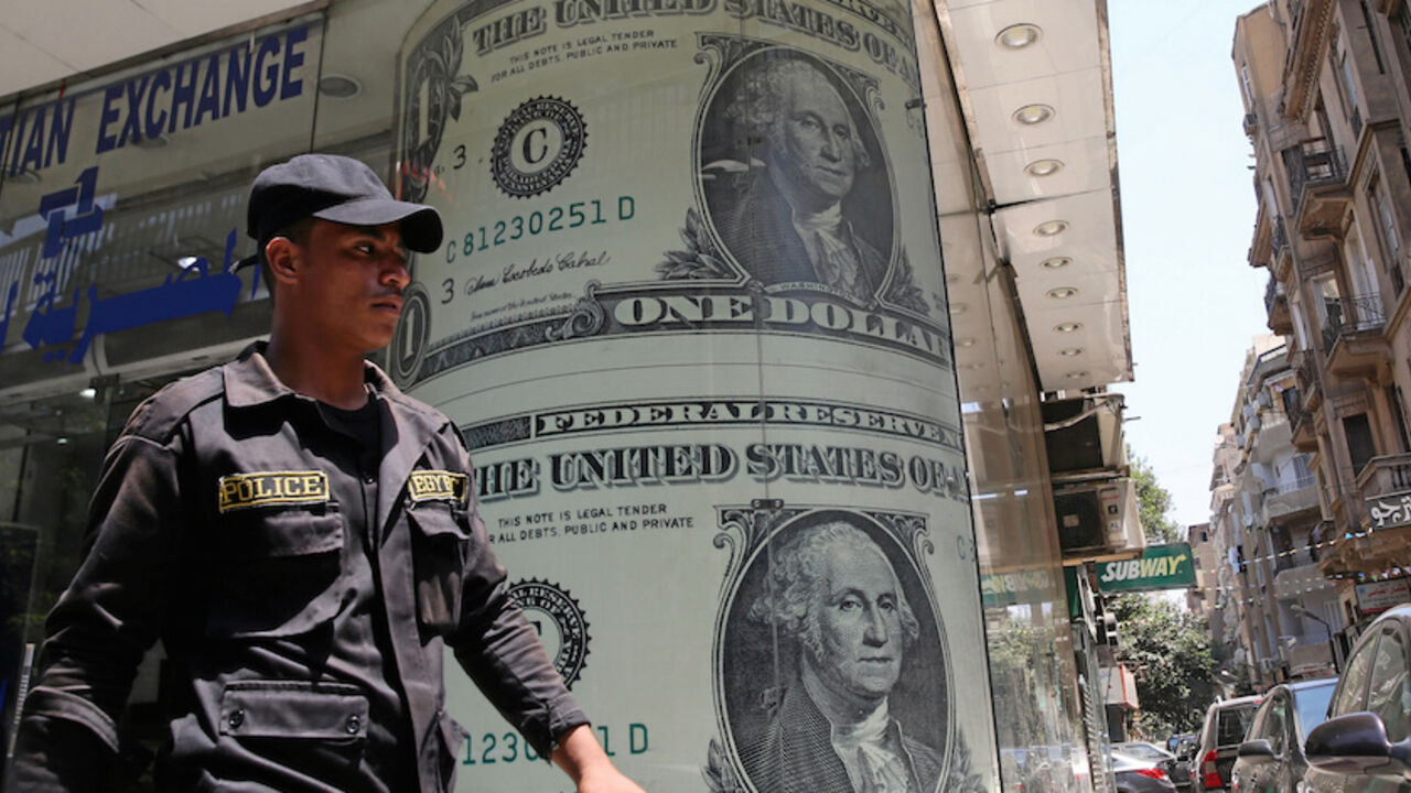 EGYPT-CURRENCY/ A policeman walks past a currency exchange bureau advertisement showing images of the U.S dollar and other currencies in Cairo, Egypt August 3, 2016. Picture taken August 3, 2016. REUTERS/Mohamed Abd El Ghany - RTSMD9F