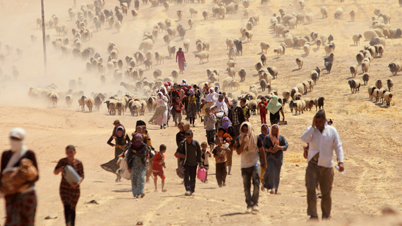 Displaced people from the minority Yazidi sect, fleeing violence from forces loyal to the Islamic State in Sinjar town, walk towards the Syrian border, on the outskirts of Sinjar mountain, near the Syrian border town of Elierbeh of Al-Hasakah Governorate August 10, 2014. REUTERS/Rodi Said/File Photo - RTX2GIYQ