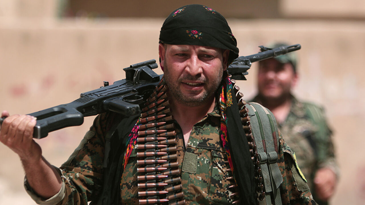 A Kurdish fighter from the People's Protection Units (YPG) carries his weapons as he walks along a street in the northeastern city of Hasaka, Syria, August 21, 2016. REUTERS/Rodi Said - RTX2MEMQ