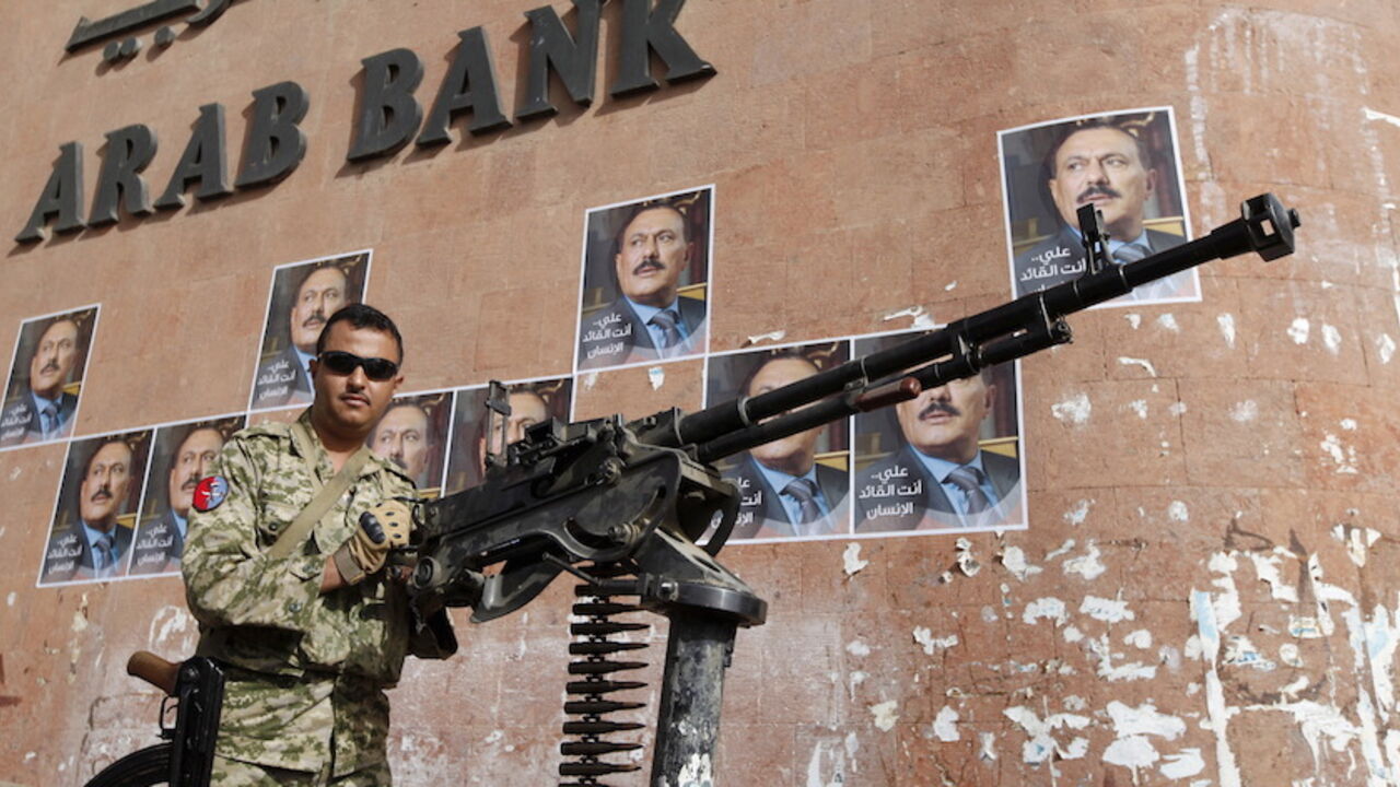 YEMEN-SECURITY/ A soldier loyal to Yemen's former President Ali Abdullah Saleh (in posters) holds a machine gun mounted on a patrol truck securing a street near a rally held by Saleh's supporters to mark one year of Saudi-led air strikes in Yemen's capital Sanaa March 26, 2016. REUTERS/Khaled Abdullah - RTSCB4F