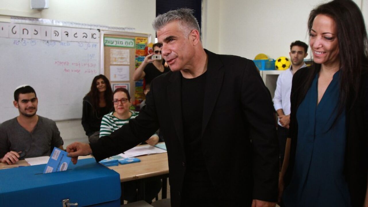 ISRAEL-VOTE-LAPID Israeli MP and chairperson of center-right Yesh Atid party, Yair Lapid, casts his ballot at a polling station with his wife Lihi (R) on March 17, 2015 in Tel Aviv. Voting polls opened for unpredictable elections to determine whether Israelis still want incumbent Prime Minister Benjamin Netanyahu as leader, or will seek change after six years. AFP PHOTO / GIL COHEN MAGEN (Photo credit should read GIL COHEN MAGEN/AFP/Getty Images)