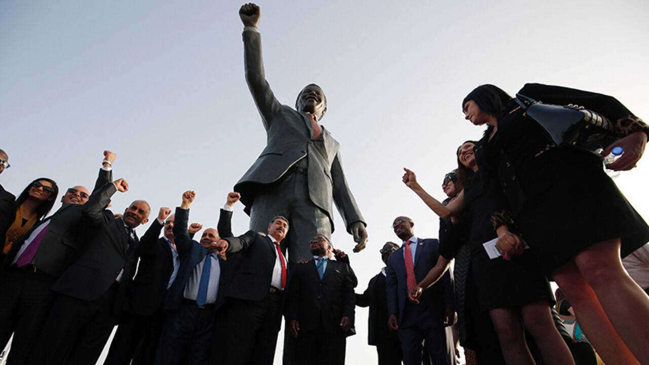 AFP_9Z9G8 Palestinian and South African officials pose in front of a giant statue of Nelson Mandela during its inauguration ceremony in the West Bank city of Ramallah on April 26, 2016.
Palestinians inaugurated the statue of Mandela donated by the South African city of Johannesburg to their political capital. The six-metre (20-foot) two-tonne bronze statue was a gift from Johannesburg with which Ramallah is twinned.
/ AFP / ABBAS MOMANI (Photo credit should read ABBAS MOMANI/AFP/Getty Images)