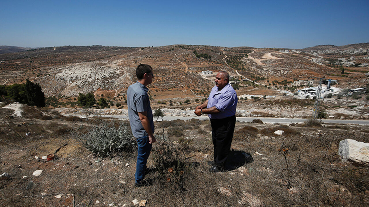 AFP_G89I6 Fuad Maadi (R), a 60-year-old Palestinian man, speaks with Gilad Grossman of Israeli rights group Yesh Din, on September 11, 2016, as he stands on a hill in the West Bank Christian village of Taybeh overlooking land he says his family owns and on which houses from the nearby wildcat Jewish settlement of Amona might be relocated.
An Israeli court has ruled that the wildcat Jewish settlement of Amona, where live around 40 families in mainly caravan homes, is on Palestinian property and must be evacuated by De
