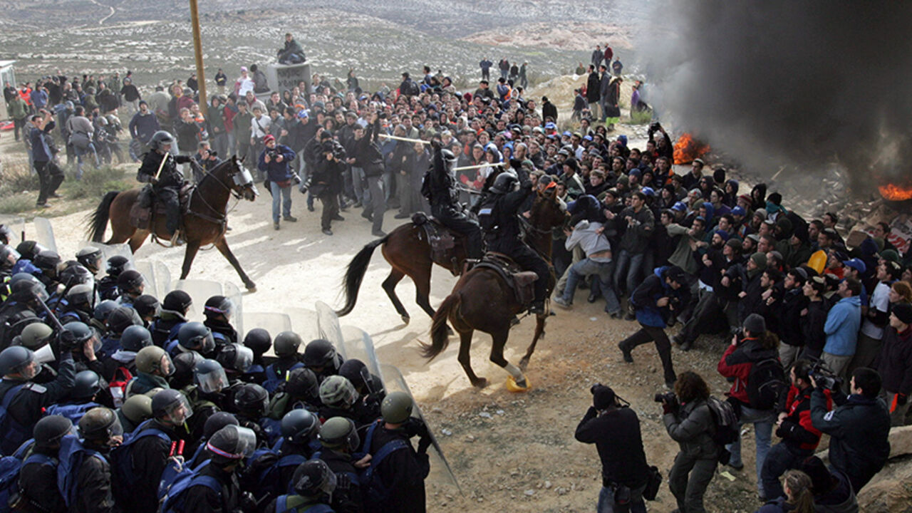 MIDEAST Israeli policemen clash with Jewish settlers at a burning barricade in the unauthorized outpost of Amona, close to the West Bank Jewish settlement of Ofra, February 1, 2006. Israeli riot police clashed on Wednesday with several thousand settlers battling to block partial demolition of an unauthorised West Bank outpost in scenes reminiscent of Israel's Gaza pullout. REUTERS/Oleg Popov - RTR19FRI